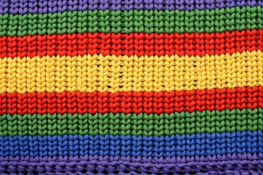 Handcrafted knit sweater adorned with a colorful spectrum of vibrant and diverse rainbow hues