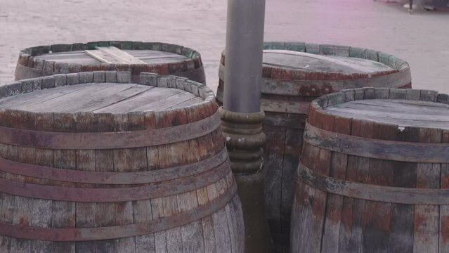 Old barrels with rusty rims stand around a pole on the street. Bondar craftsmanship and winemaking.
