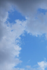Obraz premium A blue sky with white clouds and tree branches below