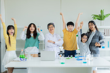Group of students and senior teacher in science classroom waving arms happy learning in private school successful experiments. cheerful diverse children participating, education concept back to school