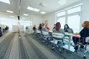 Diverse Business Team Discussing Projects in a Modern Glass Office.