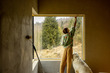 Young woman paints walls while making repairment of a new house. Creative process of home...