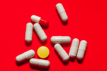 Assorted pills on vibrant red backdrop. Antibiotics for helicobacter
