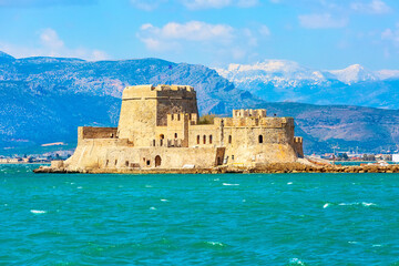 Bourtzi fortress in the sea in Nafplio or Nafplion and snow mountain peaks in Greece, Peloponnese