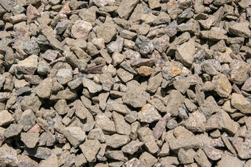 A close-up view of a pile of gray gravel stones in the sunlight