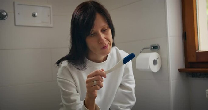Woman frustrated worry anxious with positive or negative pregnancy test unwanted unplanned pregnant fertility problem health in bathroom