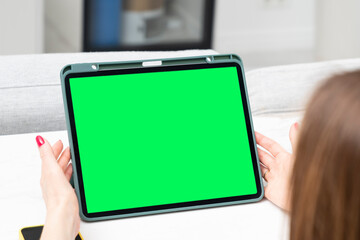 Young woman looking at her gadget with green screen