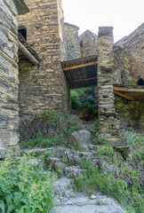 A stone path leads to the tower and the log ceiling between the walls. Streets of medieval village Shatili.
