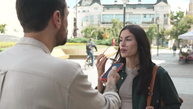 Young vlogger or journalist man street interviewing freelancer expatriate or tourist female about life or business opportunities in the city. News reporter interview strangers about positive negative