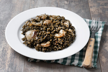 Black rice with seafood in plate on wooden table