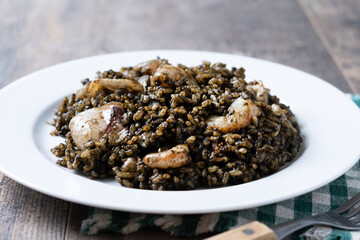 Black rice with seafood in plate on wooden table