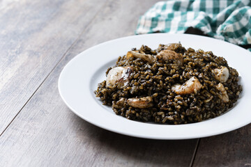 Black rice with seafood in plate on wooden table. Copy space