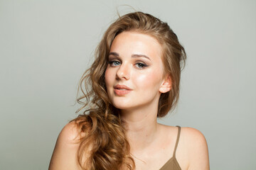 Cheerful female model with make-up, clear skin and long wavy hairstyle posing on white background....