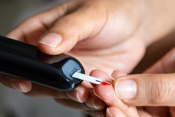 Woman's hands checking diabetes and hyperglycemia with digital blood sugar meter. Healthcare and...