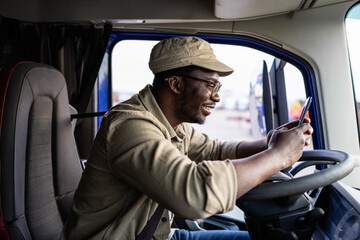 Professional driver or deliveryman using smart phone on truck stop.