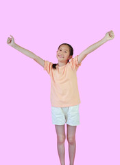 Smiling Asian young girl child raised hands up showing winner gesture while standing isolated on pink studio background. Image with Clipping path.