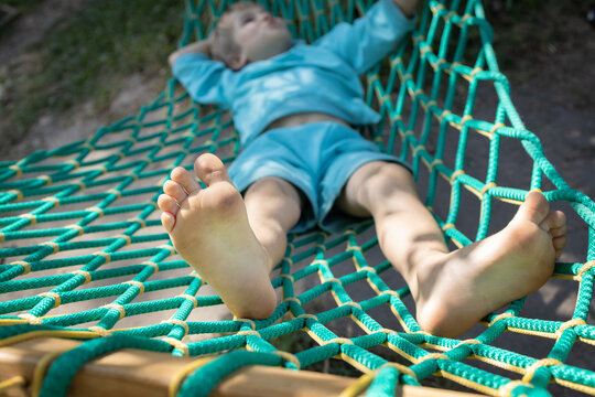 barefoot child relaxes while lying in a hammock. Lifestyle. enjoy life. Summer holidays. Happy childhood concept. Entertainment for children. Focus on feet
