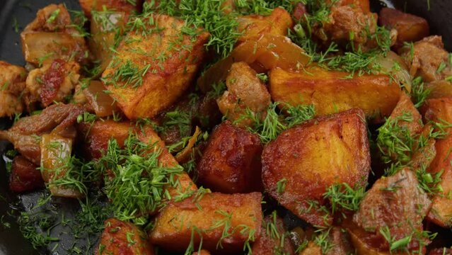 Fried potatoes with meat and herbs in a plate. Close-up. Selective focus.