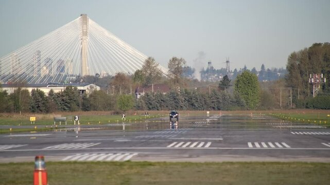 Airport Inspection Vehicle Drives on Runway, Port Mann Bridge Backdrop