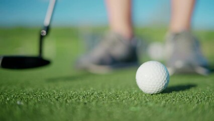 Close up of a man practicing hitting a golf ball with a club on the course