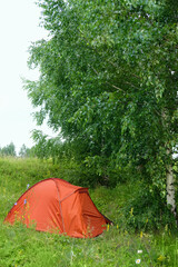 orange tourist tent in green forest, natural background. active holidays. freedom adventure, privacy, unity with wild nature, tourism, travel concept. landscape with Camping place. forest scenery