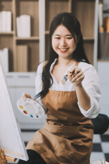 Pretty talented female painter painting on easel, making colorful sketches, creating marine landscape. Beautiful female artist painting with watercolor paints. Creativity and imagination concept