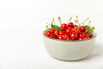 Cherries. Fresh ripe cherries with leaves on a textured wooden background. Fresh sweet organic cherry pile. Berries and fruits. Vegan. Healthy eating. Place for text. Copy space