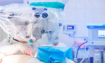 Abstract medical blurred background of operating room with blue light, patient lies on table, doctors working