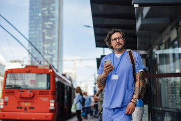 Doctor wating foth the bus at bus stop, going home from work. Work-life balance of healthcare...