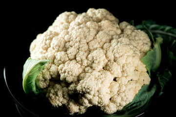 Raw cauliflower in a plate on a black background.Vegetables concept