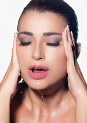 Close-up of beautiful woman with water on her face showcasing moisturized skin and waterproof makeup