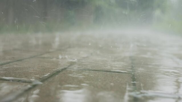 Close-up of raindrops falling on sidewalk. Rainy day. Bad weather with heavy rain