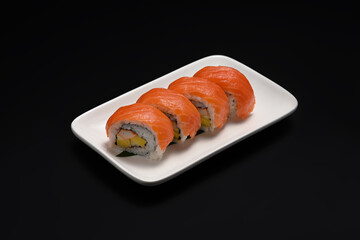 California salmon roll or Uramaki sushi served in plate on black background. Japanese food style concept