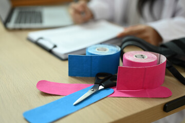 Kinesio tapes and scissors on table at physiotherapist office. Rehabilitation, treatment and healthcare concept