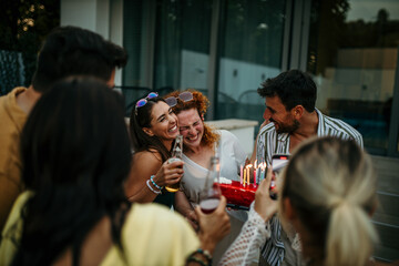 Group of multi racial friends celebrating the birthday of their female friend during a garden party