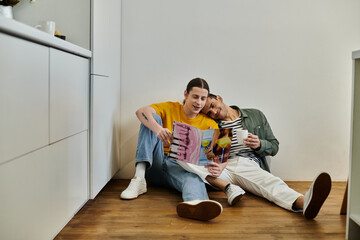 A young gay couple relaxes in a modern apartment, sharing a moment of intimacy while reading a...