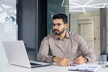 Serious and concentrated thinking businessman watching webinar online course, man upgrading at...
