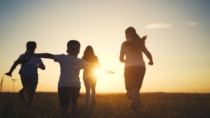 Fototapeta premium Silhouette of a group of children running. Concept friends many concept. Silhouette of a family running in the park. Silhouette of a family and lifestyle children running in the park.
