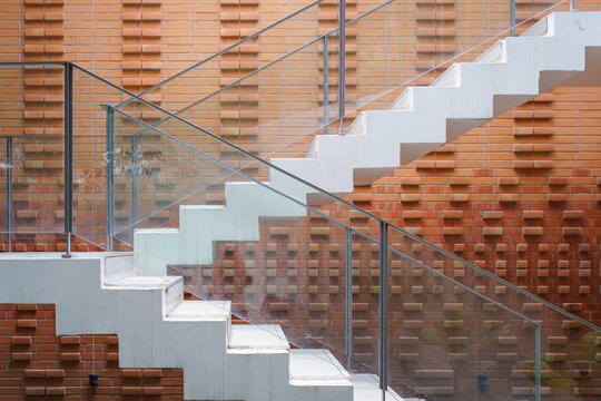 Stairway with stainless steel metallic banister in a new modern building architecture exterior and brick blocks wall or red terracotta bricks wall background.