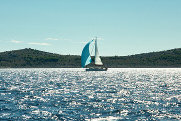 A sailboat is sailing in the ocean with a blue sail