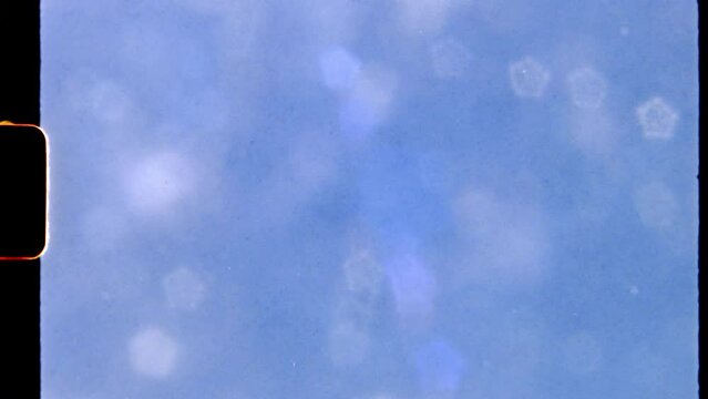 super 8mm vintage film a white fluffy cloud under blue sky. a view from through beautiful sunny 