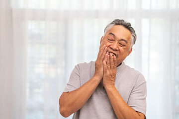 Senior asian man experiencing tooth pain, holding his cheek with pained expression, discomfort and...