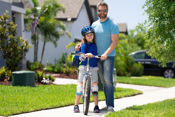 Fathers day. Father teaching son ride a bicycle. Father and son cycling on bike on summer day. Father support child. Fathers love. Sporty kids. Cute boy with dad cycling in summer park outdoor.