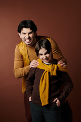 A father and son stand close together, both with playful expressions on their faces.