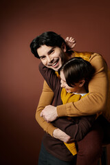 A father and son share a loving embrace in a studio setting, capturing a moment of pure joy.