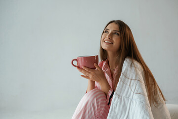 Big cup of drink. Morning, waking up. Young pretty woman is against background in the studio