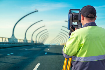 Man surveyor. Geodetic surveys during road construction. Surveyor stands on bridge. Construction...