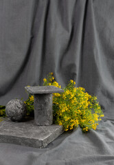 There is a podium on a gray draped background and a bouquet of yellow flowers
