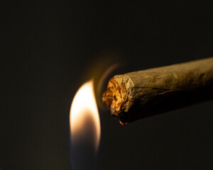 Macro shot of lighting a rolled cigarette isolated on the black background.