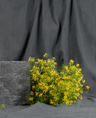 There is a large podium and a bouquet of yellow flowers on a gray draped background